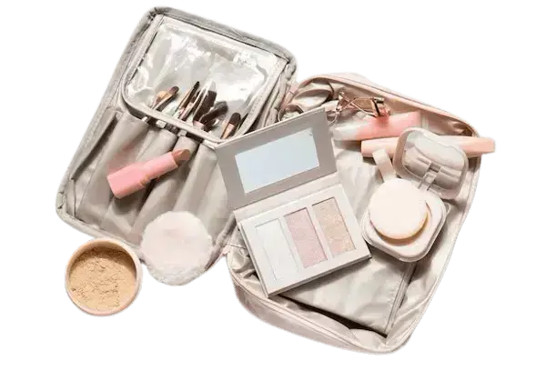 An open beige makeup travel bag filled with makeup brushes, lipstick, powder, a highlighter palette, and an eyelash curler.